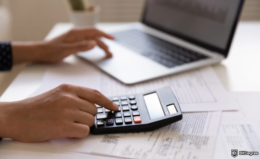 Buy XRP with PayPal: hands touching a laptop and a calculator to illustrate fee calculation.
