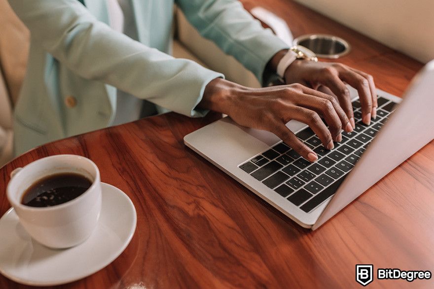 Bybit affiliate: a person using a laptop with a cup of coffee besides them.