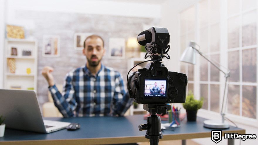 Bybit affiliate: a person sitting at a desk recording content in front of a camera.