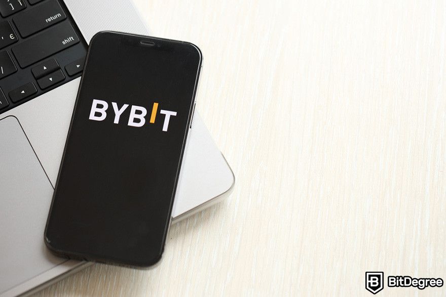 Bybit affiliate: a mobile phone displaying Bybit's logo on a laptop.