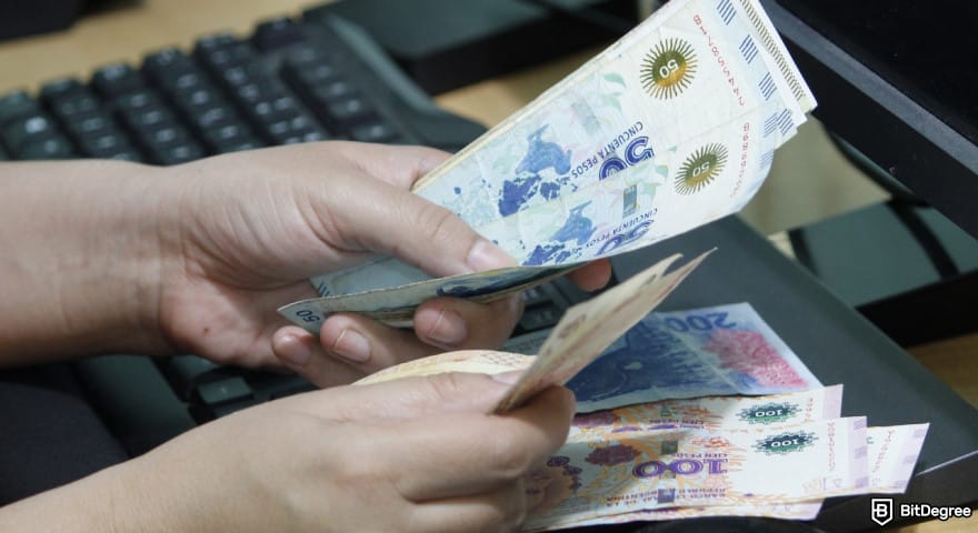 Bybit taxes: a person holding several bills of Argentine Peso in hand.