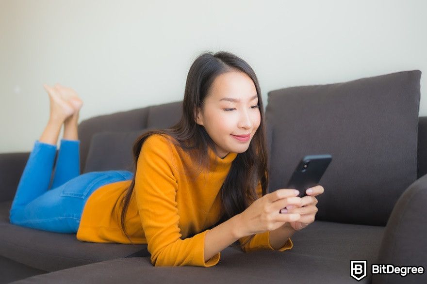 Chainlink staking: a woman casually checking a phone on a sofa.