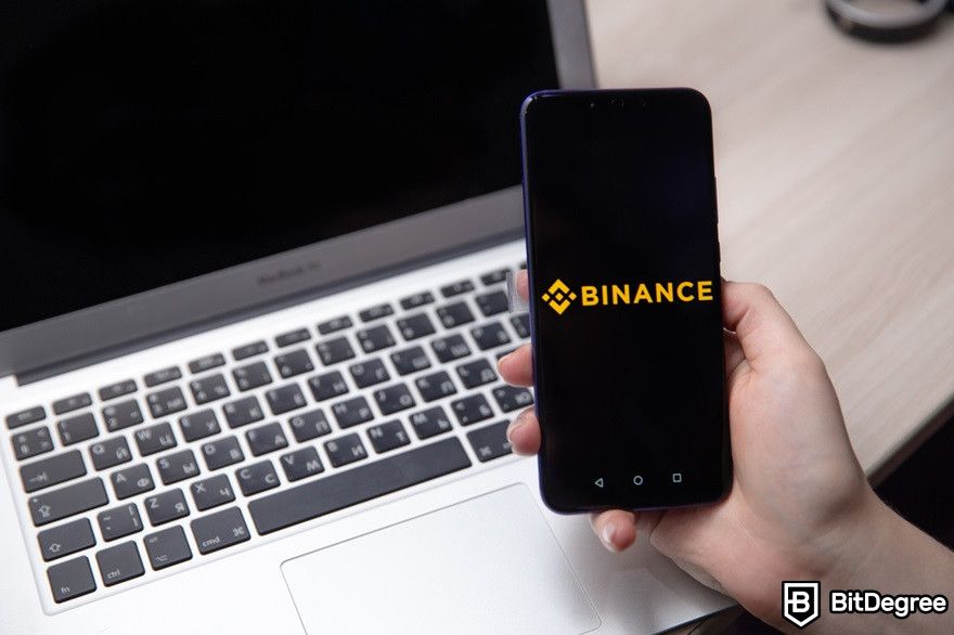 Chainlink staking: Binance logo displayed on a mobile phone near a laptop.