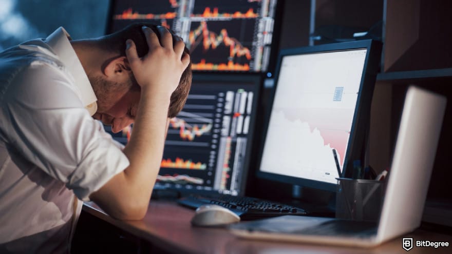 Chinese crypto coins: young businessman holding hands on his face while sitting at the desk.