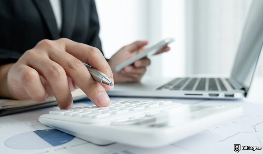 Coinbase Wallet taxes: a person holding a phone and a calculator to illustrate tax calculation.