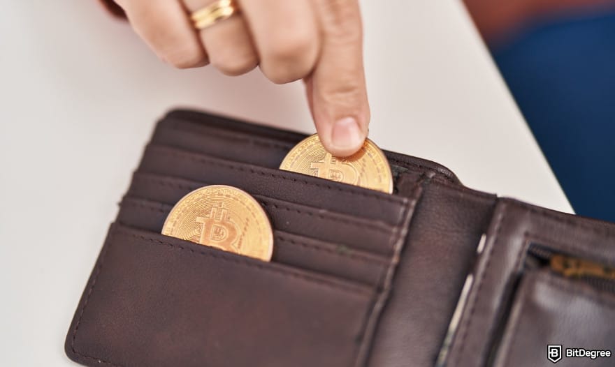 Coinbase Wallet taxes: a woman putting a Bitcoin inside a wallet to illustrate crypto wallet.