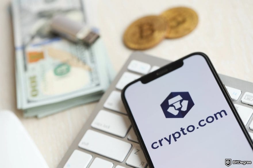 Crypto.com review: Crypto.com app on phone, with cash and Bitcoin in the background.