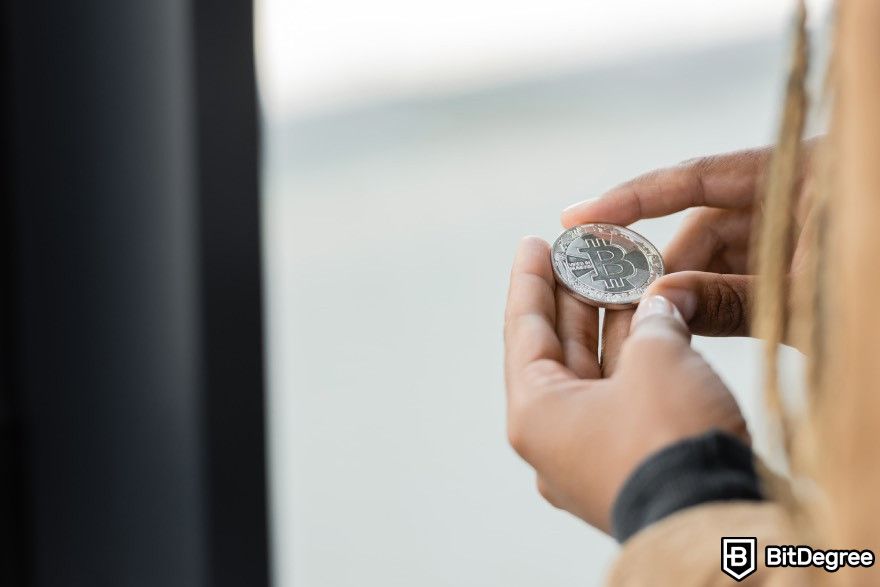 Crypto signals Telegram: Person holding a Bitcoin.