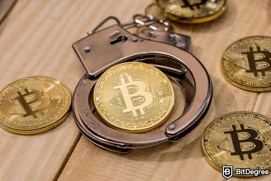 Crypto vs stocks: handcuffs encircling a Bitcoin coin on a wooden surface.