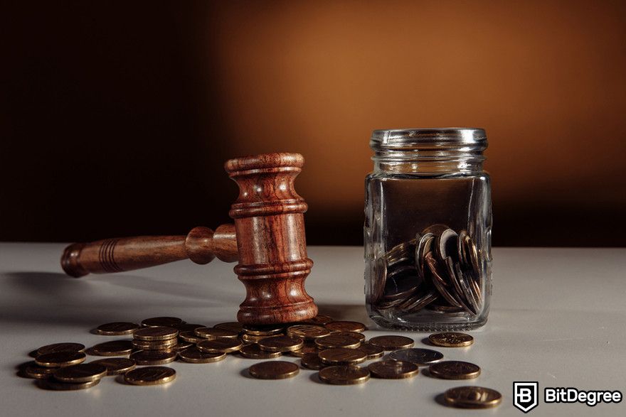 Crypto vs stocks: a judge's gavel next to a jar filled with cryptocurrency coins.