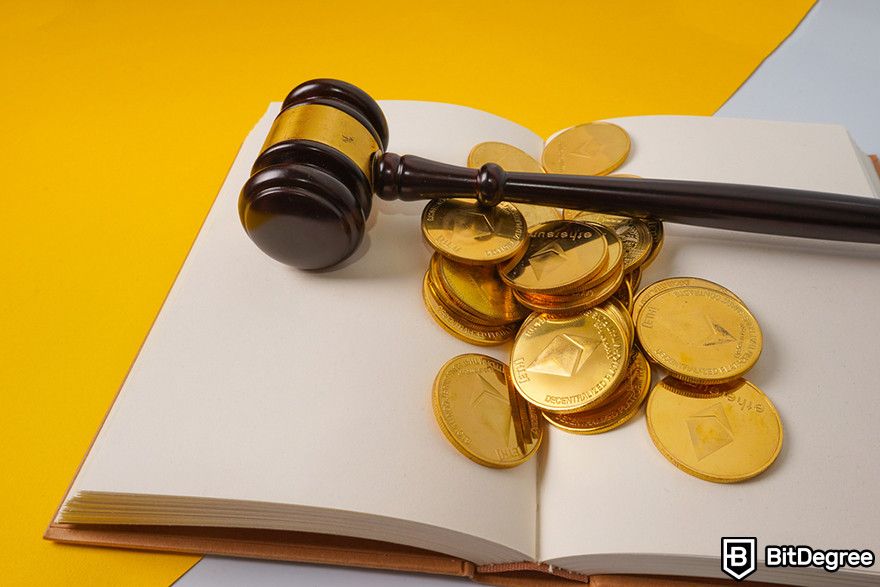 Crypto vs stocks: judge's gavel resting on a pile of cryptocurrency coins atop an open book.