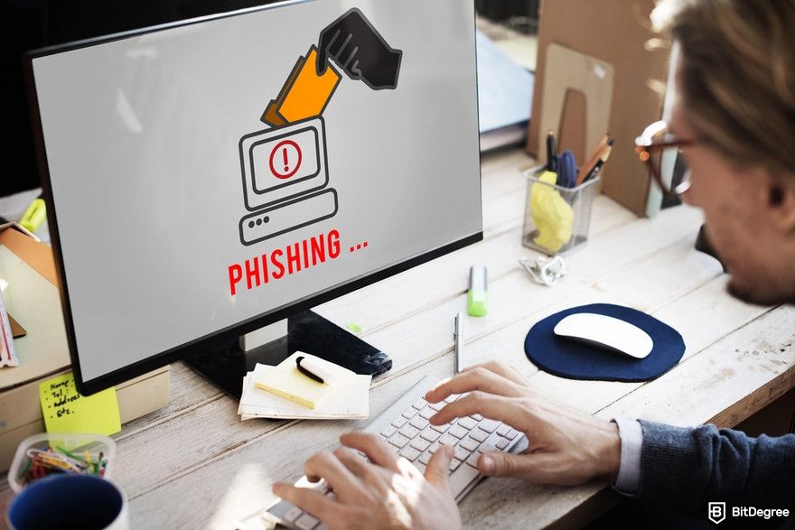 Crypto wallet security: a man in front of a computer showing the PHISHING text.