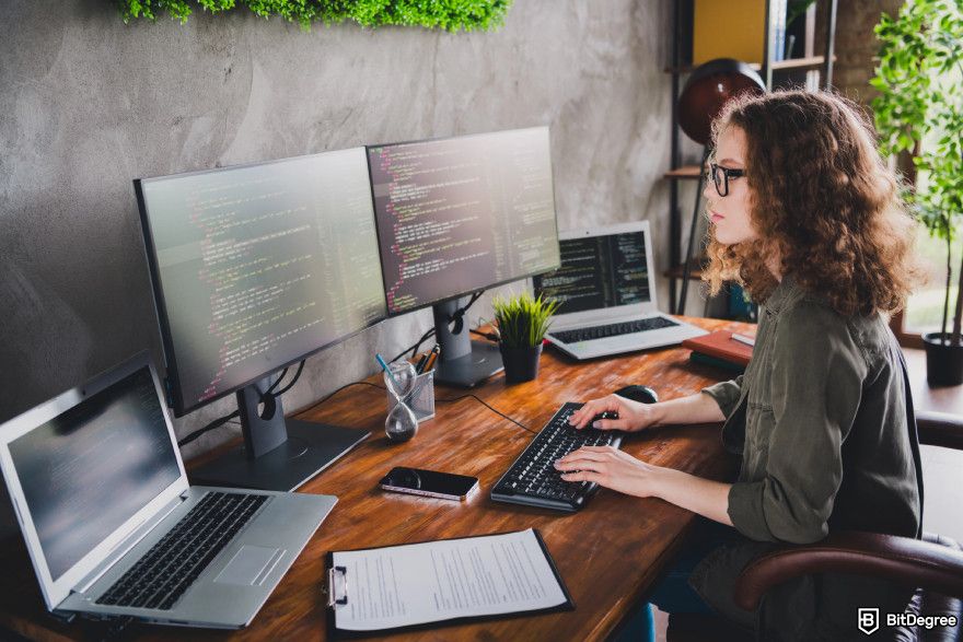 Cryptocurrency jobs: a female developer working on multiple screens.