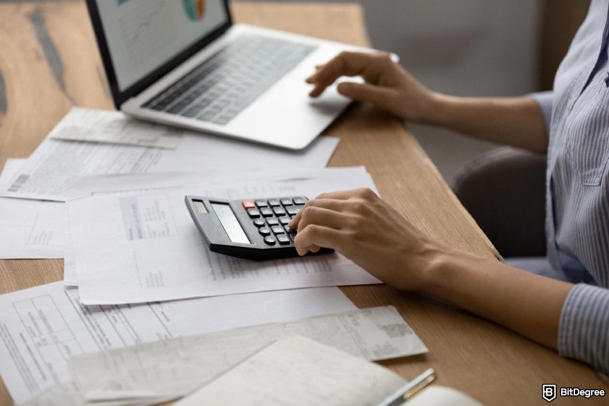 Cryptocurrency jobs: a financial specialist working on different materials and calculator.