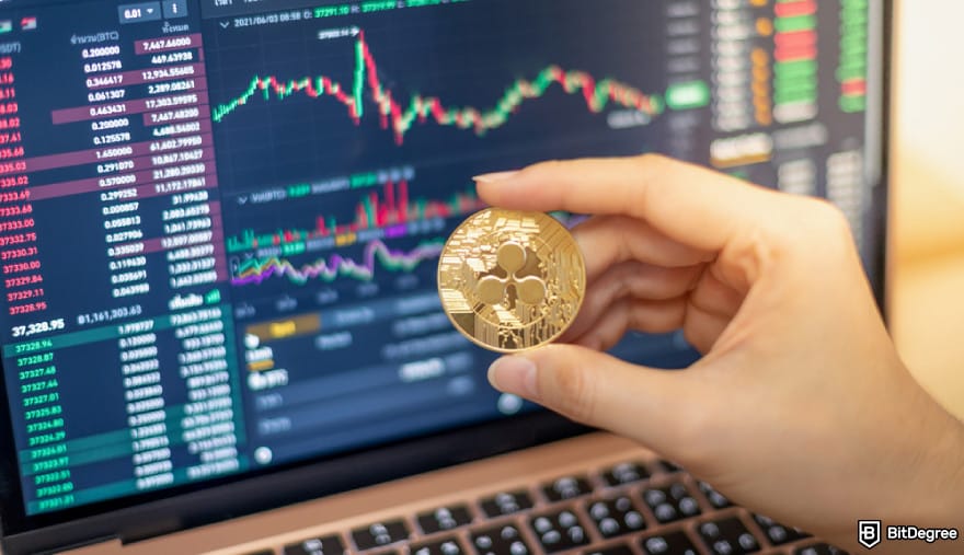 Cryptocurrency regulation SEC: Ripple coin in front of a computer with analytics chart.