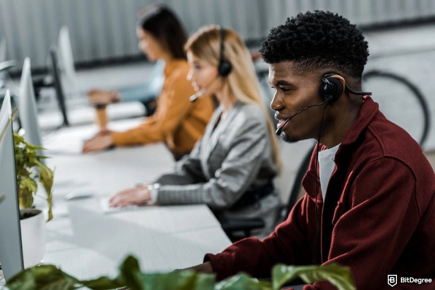 CryptoWatch review: several person using desktops while wearing headphones.