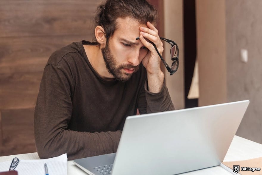 CryptoWatch review: a person looking at a laptop with a frustrated expression.