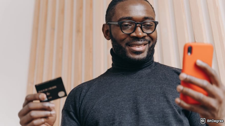 Currency devaluation in Nigeria: a person holding a credit card and a smartphone.