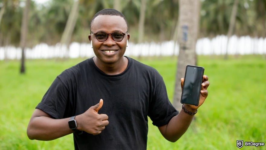 Currency devaluation in Nigeria: man outdoors holding a smartphone and giving a thumbs-up.