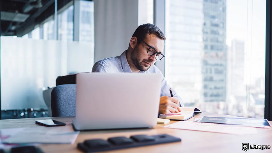 DataCamp vs Codecademy: A man taking notes during an online course.