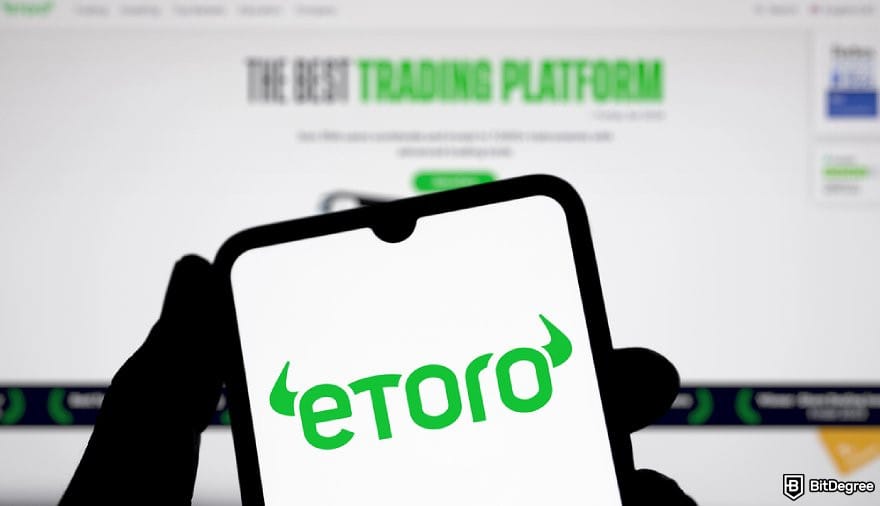 eToro review: a hand holding a phone displaying eToro logo.