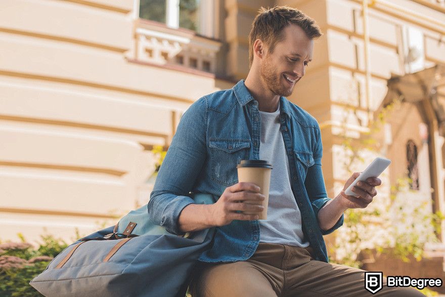 Fractional NFTs: a person holding a paper cup of coffee and a smart phone while smiling.