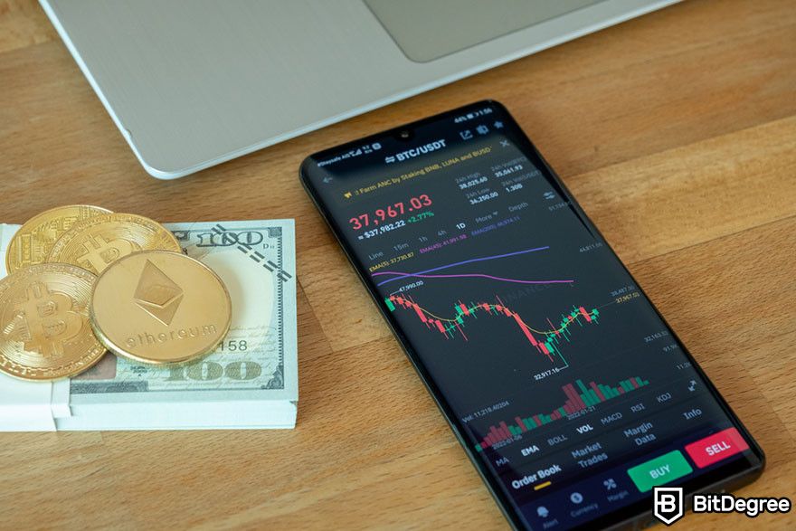 Future of blockchain: Bitcoin and Ethereum coins on top of a stack of 100 dollar bills beside a mobile phone showing the price of BTC to USDT.