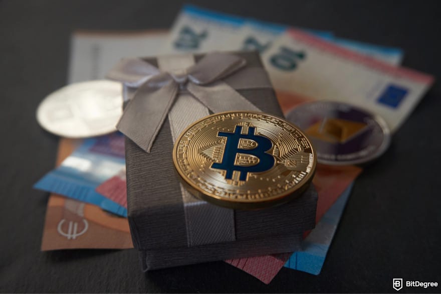Gemini Credit Card Review: a Bitcoin on top of a gift box lying over Euro notes.