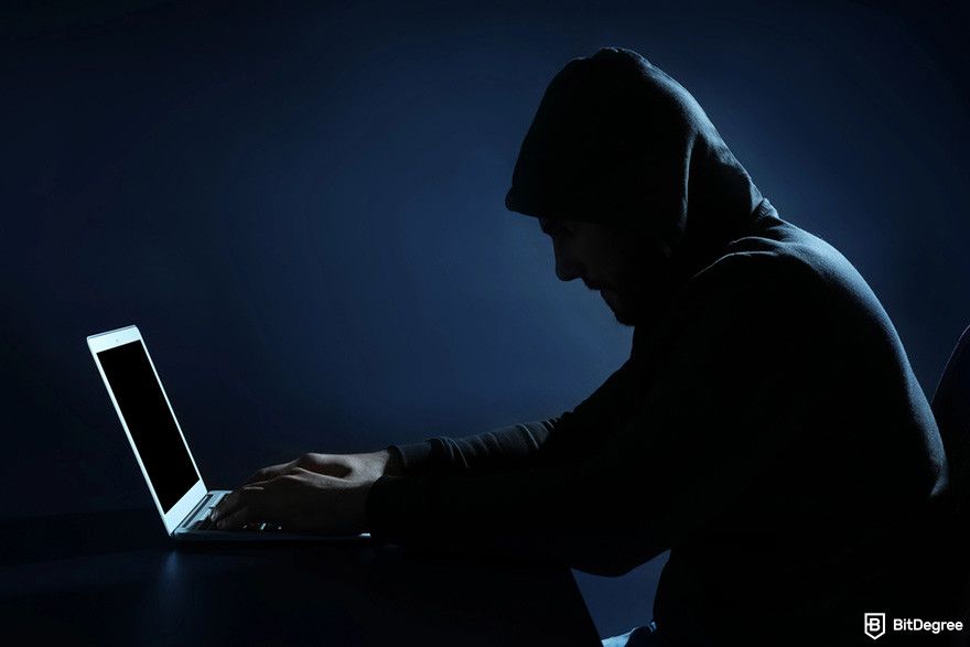 GMX review: a person wearing a hoodie sitting in front of a laptop in a dimly lit room.