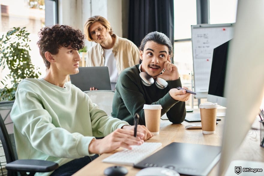 Google Analytics 4 courses: three person looking at a desktop monitor.