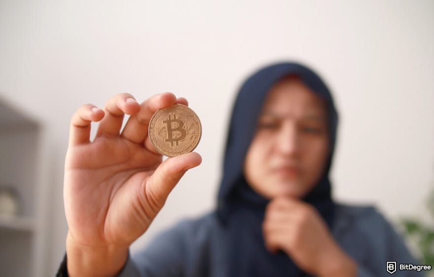 Halal crypto list: Muslim woman holding a Bitcoin.
