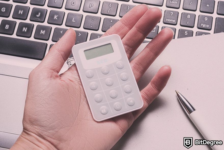 Hard token vs soft token: a person holding a security token on top of a laptop keyboard.