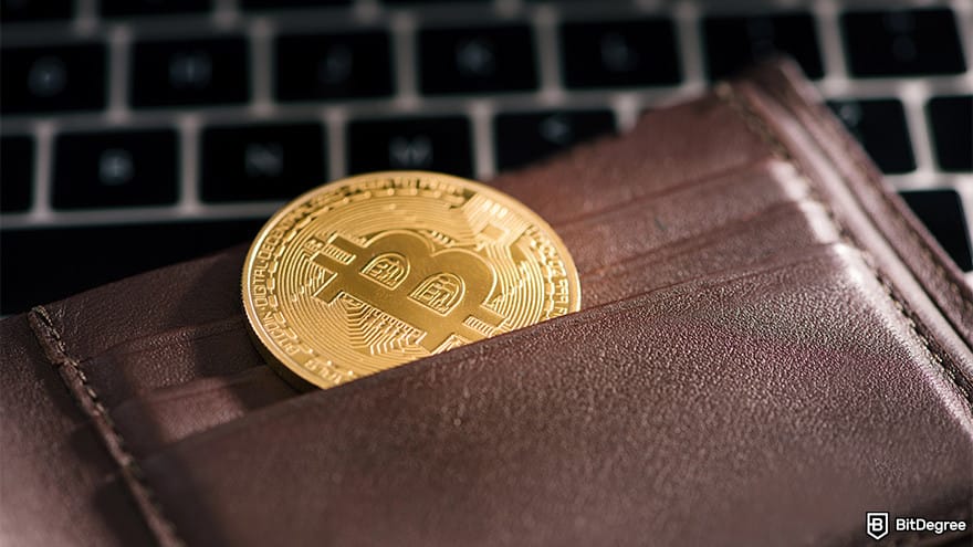 Highest paying Bitcoin faucet: Bitcoin placed inside a wallet and left on top of a laptop.
