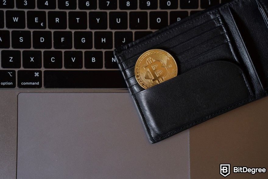 Highest paying Bitcoin faucet: Bitcoin placed inside a wallet and left on top of a laptop.