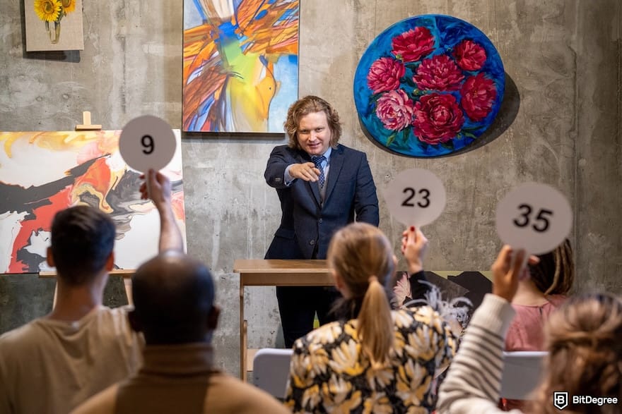 How to avoid ETH gas fees: a male auctioneer pointing at one of people with auction paddles.