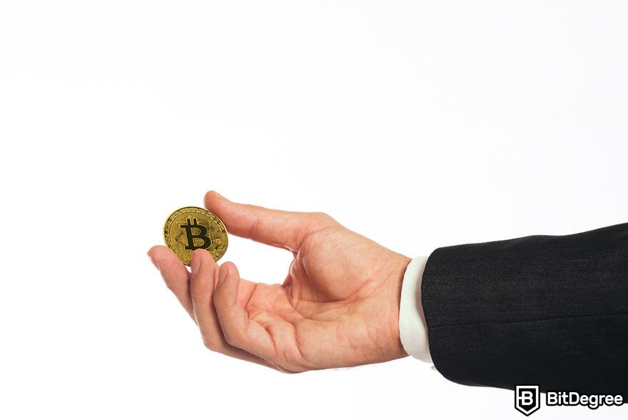 How to borrow against Bitcoin: a hand holding a BTC coin.