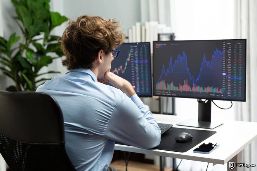 How to buy Cardano: a person looking at price charts on desktop monitors.