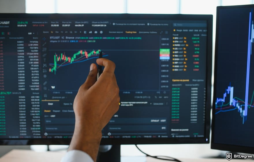 How to buy CARDS token: hand pointing at trading screen to illustrate crypto trading.