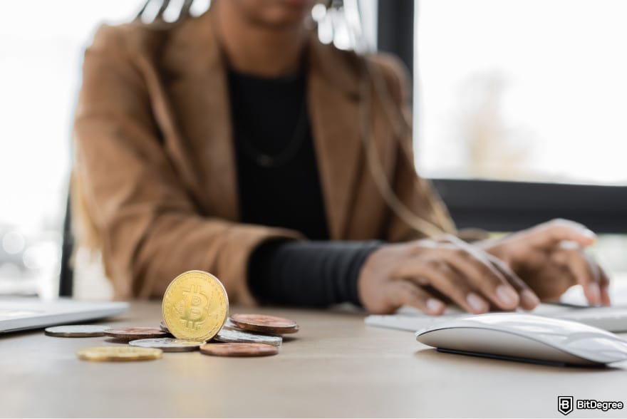 How to buy MORPHO: a person typing on a computer with a few Bitcoins lying around.