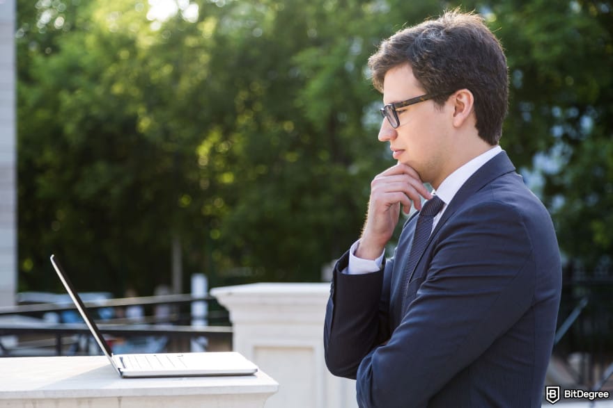 How to buy Qubetics crypto: a frowning businessman staring at a laptop screen with concern.