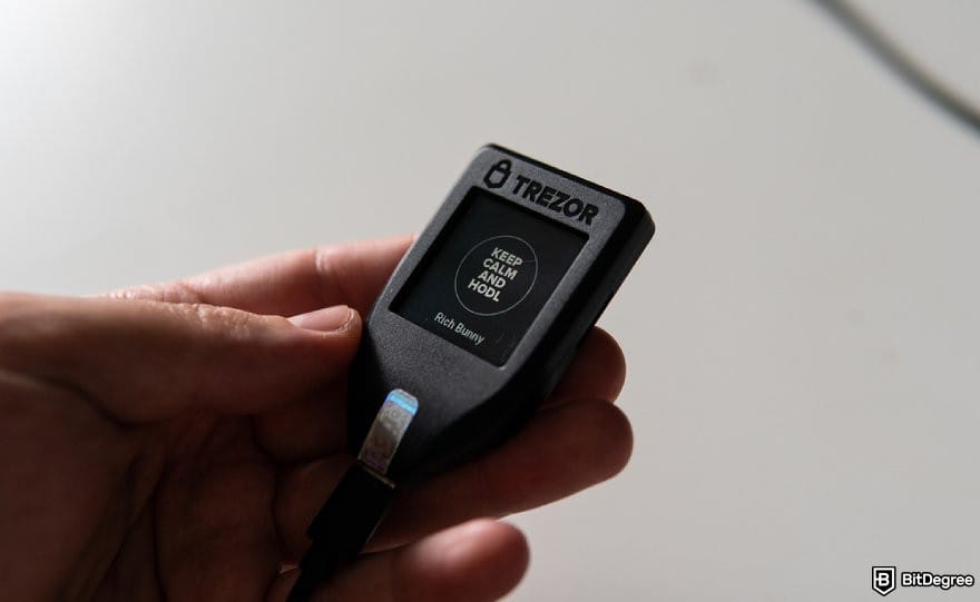 How to buy USUAL crypto: a hand holding a Trezor hardware wallet.