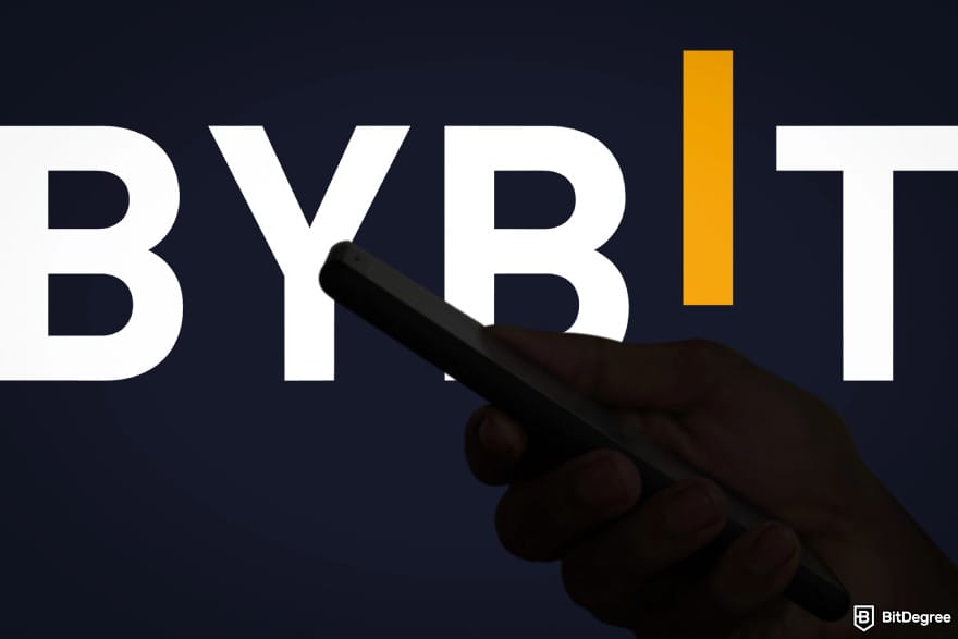 How to buy XYZVerse: a hand holding a phone with Bybit in the background.