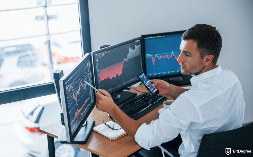 How to choose a crypto exchange: a man working at a desk with three screens.