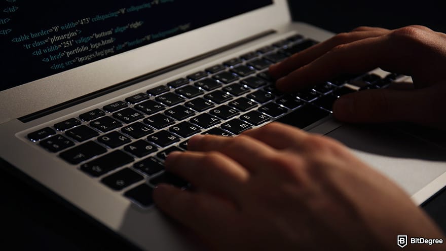 How to code for beginners: A person typing on a laptop in a dark setting.