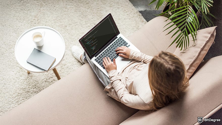 How to code for beginners: A woman typing on a laptop in a living room.