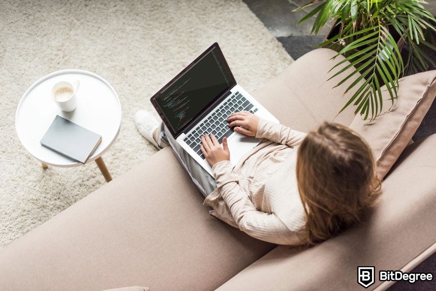 How to code for beginners: A woman typing on a laptop in a living room.