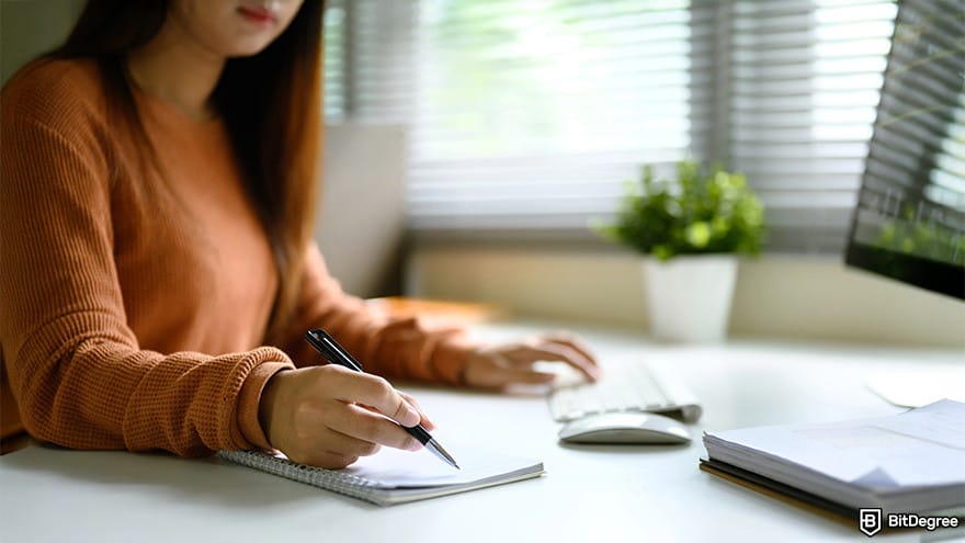How to code for beginners: A person writing in a notebook and working with a computer.