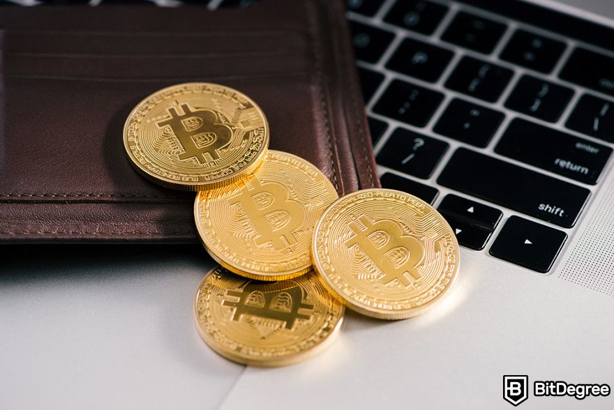 How to get a crypto wallet: Bitcoin coins and a wallet on a laptop.