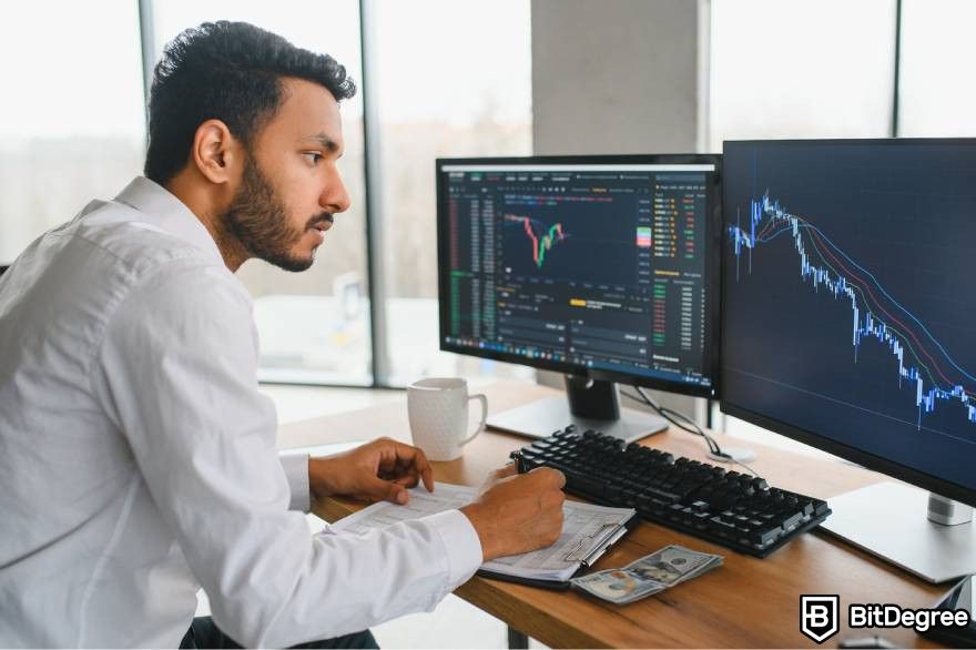 How to invest in Web3: A trader at a desk with two monitors showing market graphs