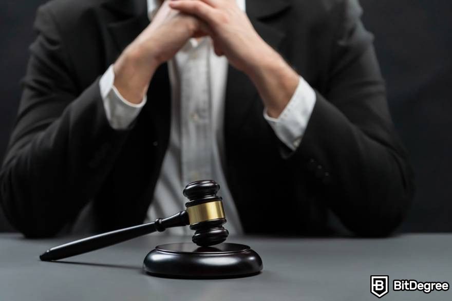 Cardano Staking: focus wooden gavel hammer with burred background of a man in black suit.